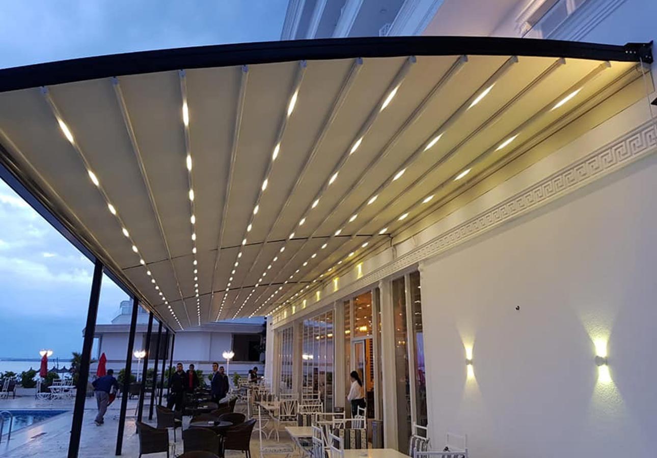 LED-lit awning pergola over a terrace at night