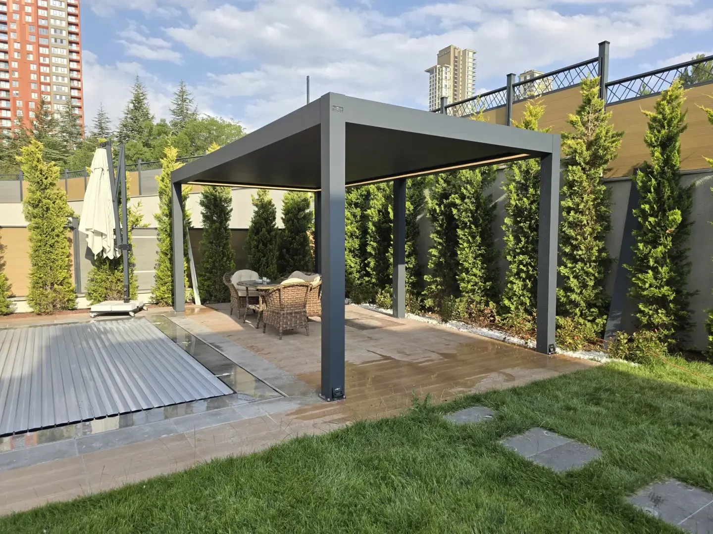 Anthracite bioclimatic pergola in a garden with a green wall