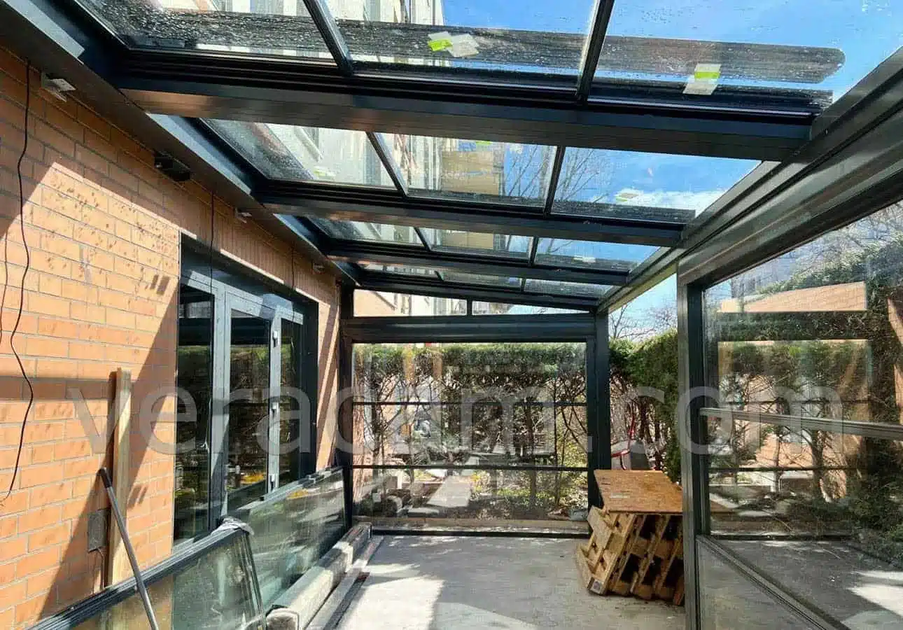 Retractable glass roof garden room attached to a brick house
