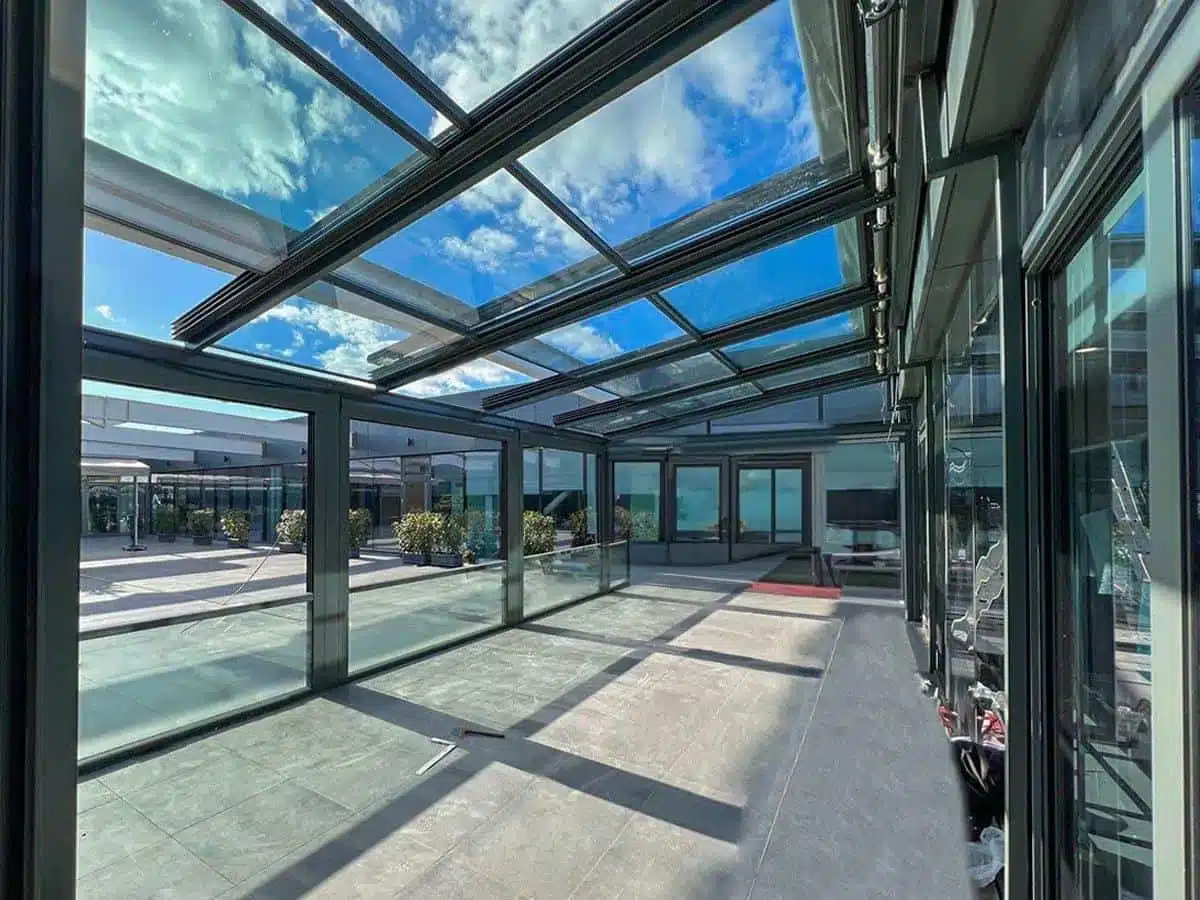 Motorised retractable glass roof over a sea-view terrace with glass walls